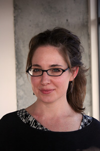 Ms Gourley standing in front of a grey and white wall