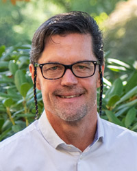Dr. Thompson standing in front of some bushes